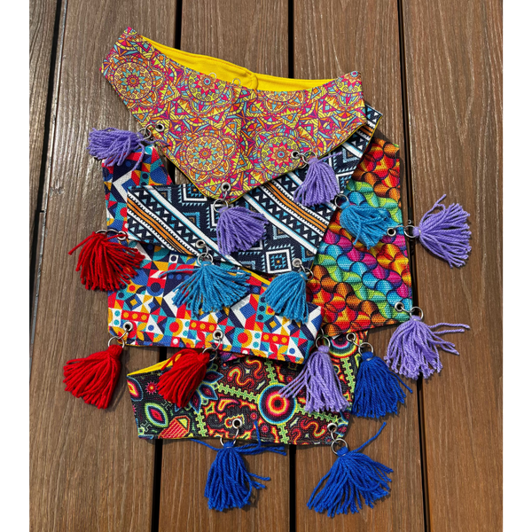 A collection of colorful dog bandanas  with pom poms from Mexico