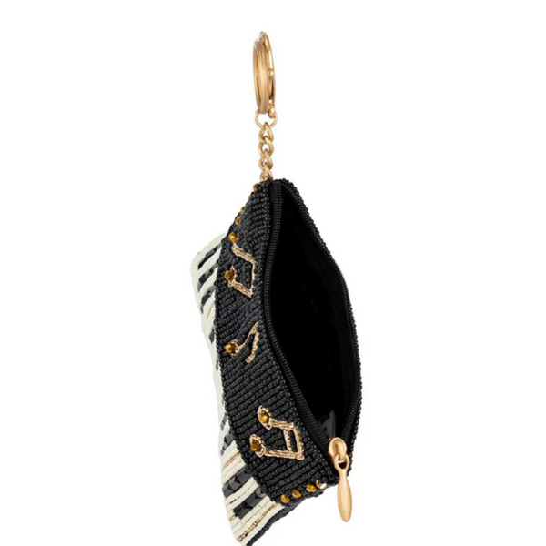 Top view of a black and gold beaded coin purse with a piano design, featuring music notes and a key ring attachment.