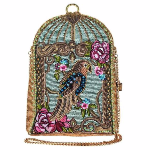 A blue beaded handbag featuring a detailed parrot design with floral patterns and a gold-tone cage-like structure by Mary Frances.